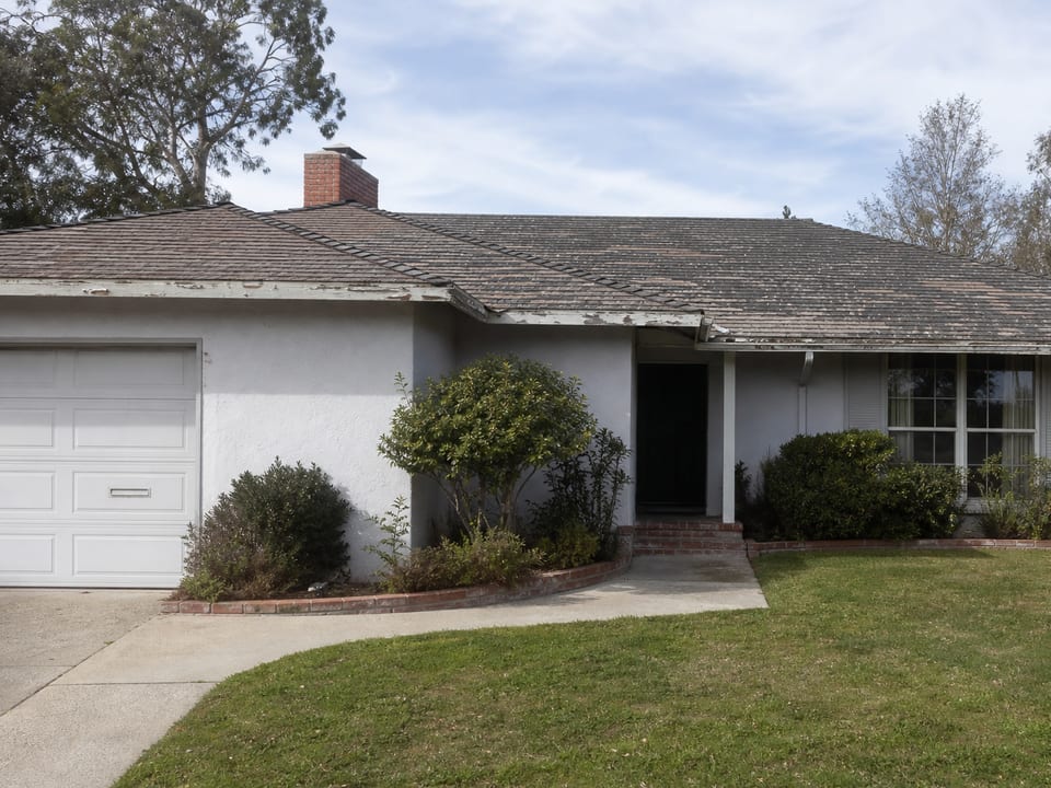 Before photo: home with sagging gutters and faded, patchy roof shingles