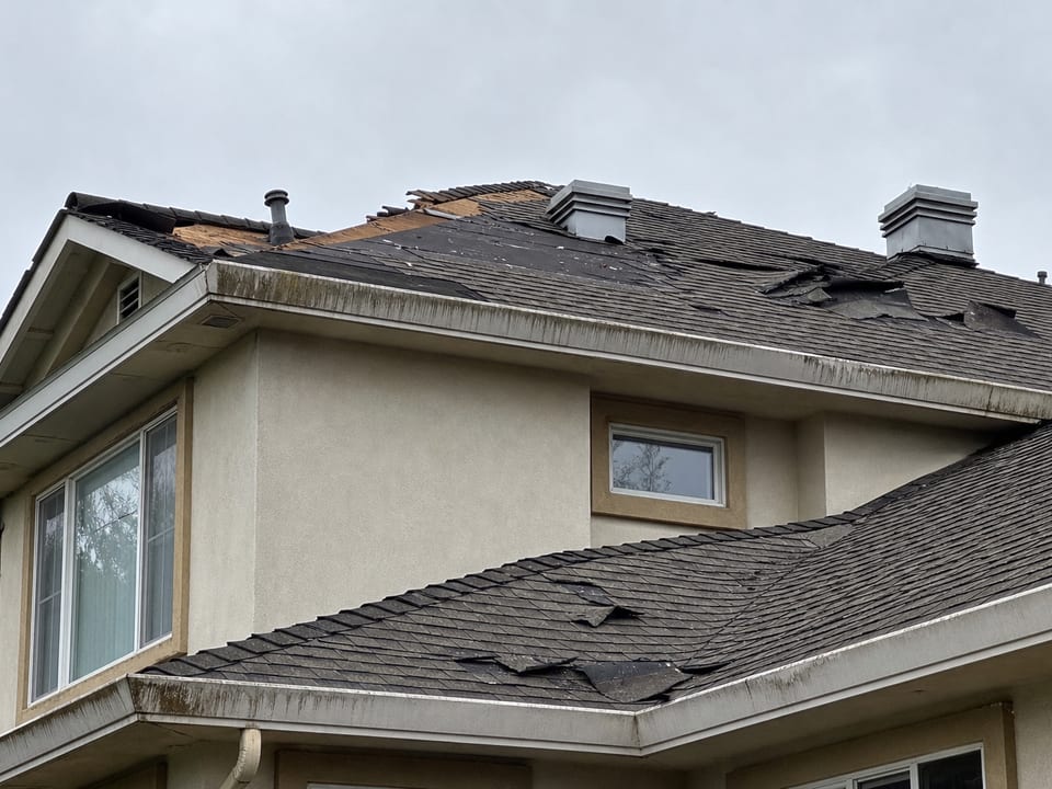 Before photo: roof with wind-lifted shingles and visible water staining